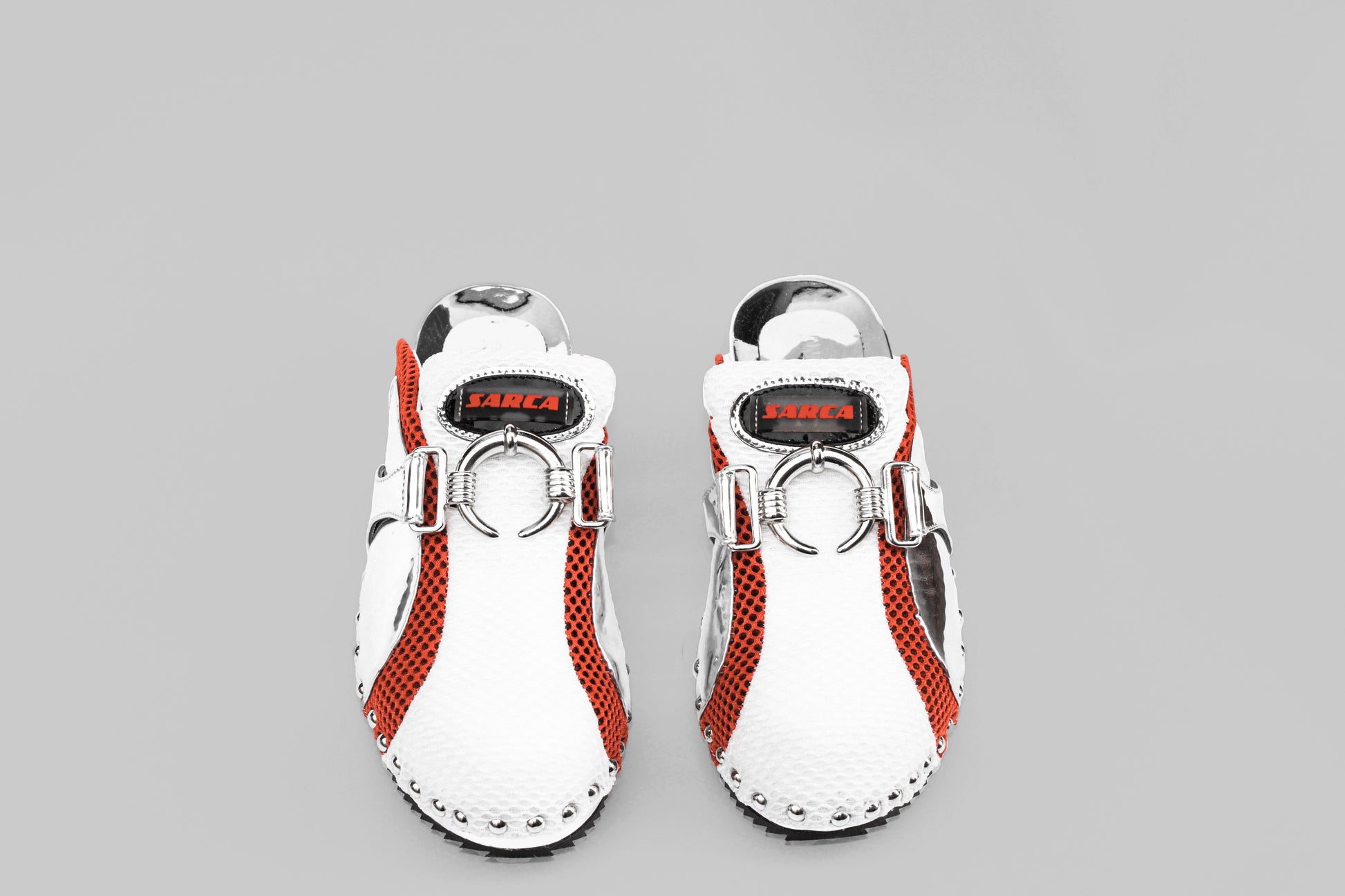 A photograph of the top view of a pair of Ancuta Sarca Beetle Clog Mirror shoes, MIRROR FINISH, MESH PANEL WITH RING EMBELLISHMENT, LOGO PATCH AT TONGUES, BRANDED FOOTBEDS, ROUND TOES, SILVER TONE HARDWARE, MADE IN ITALY