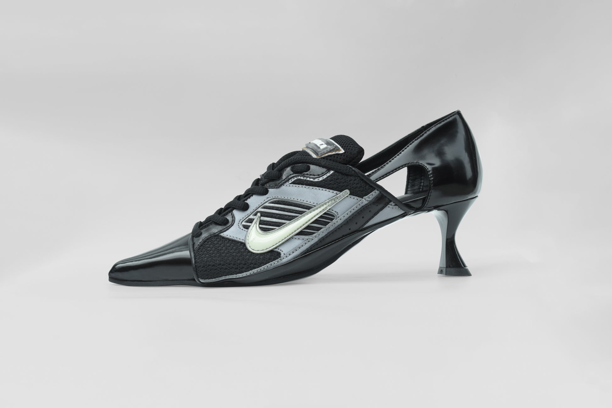 A photograph of the side view of Ancuta Sarca Lamborghini Heel Black, 6CM HEEL, UPCYCLED TRAINER CLOSED BACK PUMPS, POINTY TOE, BLACK FAUX LEATHER